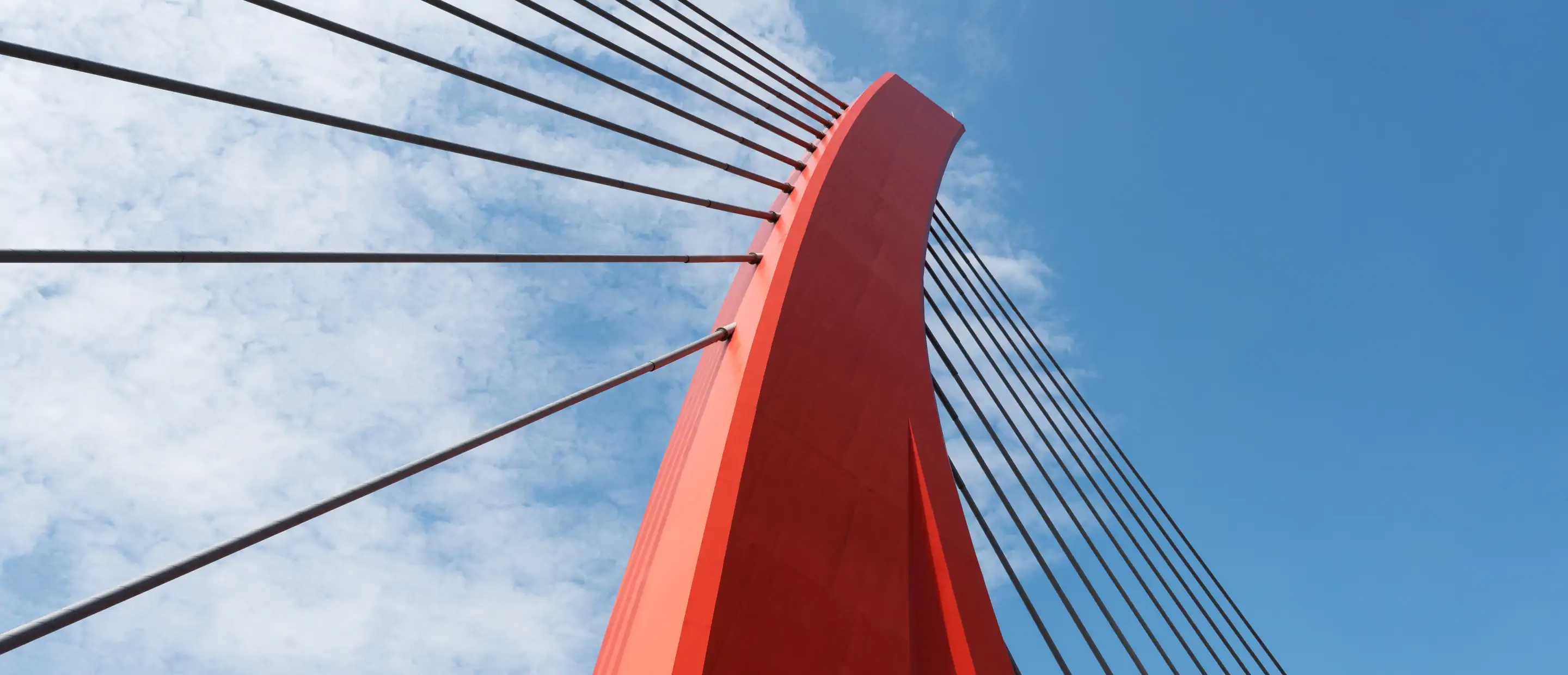 Red cable bridge against blue sky