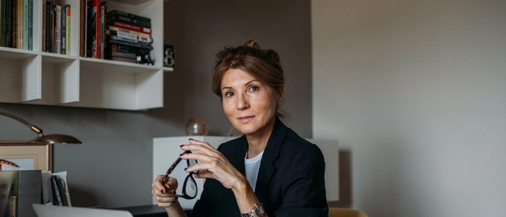 Woman at a desk holding a pair of glasses