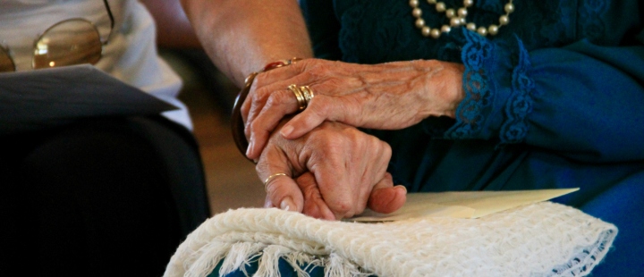 Two people holding hands while seated side by side.
