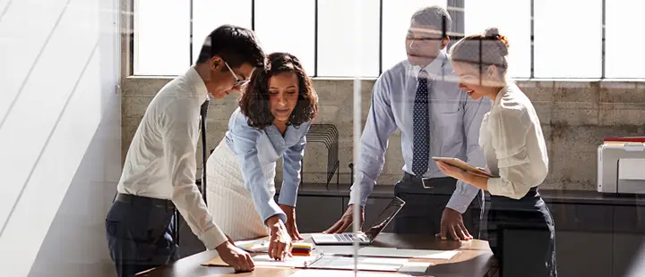 People in discussion surrounding a desk